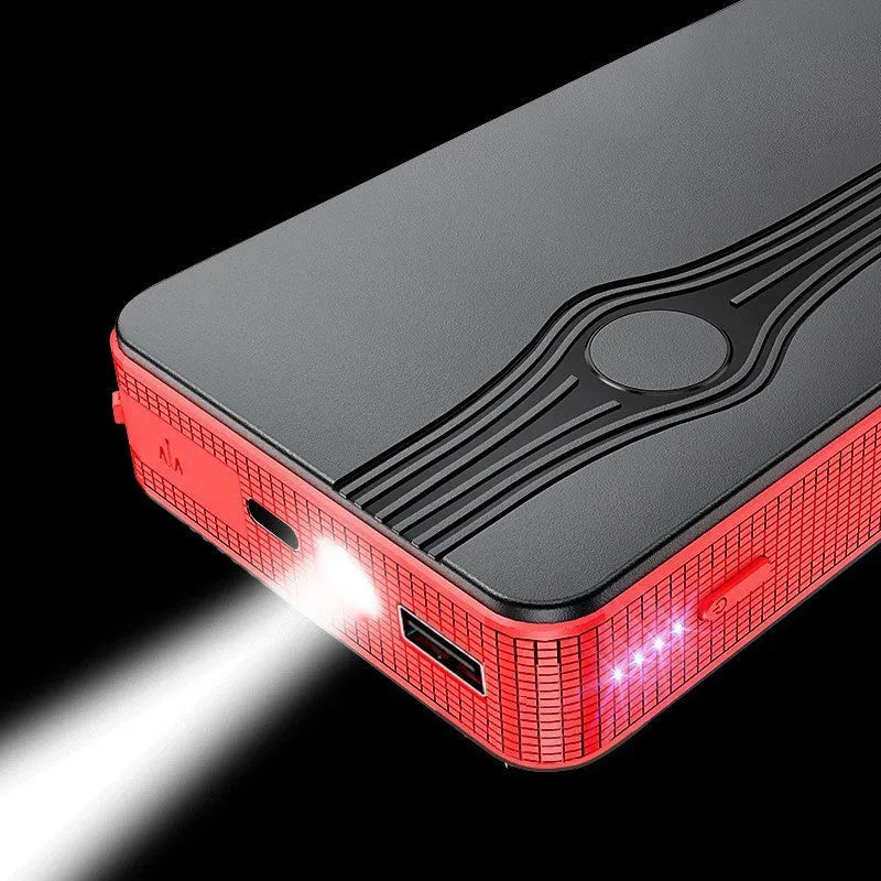 Red K4-E portable car jump starter and power bank unit with USB cable on a table.