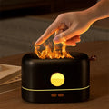 Black USB humidifier diffuser with flickering flame effect light and water mist on wooden desk