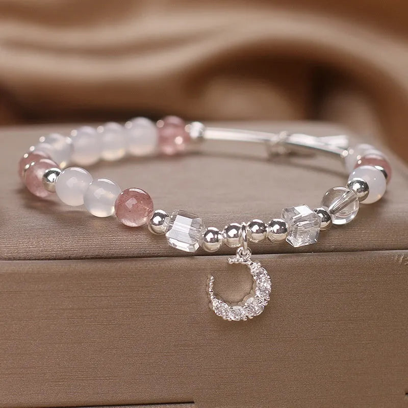 Natural strawberry quartz bracelet with pink cube sugar beads and moon pendant on a flat surface
