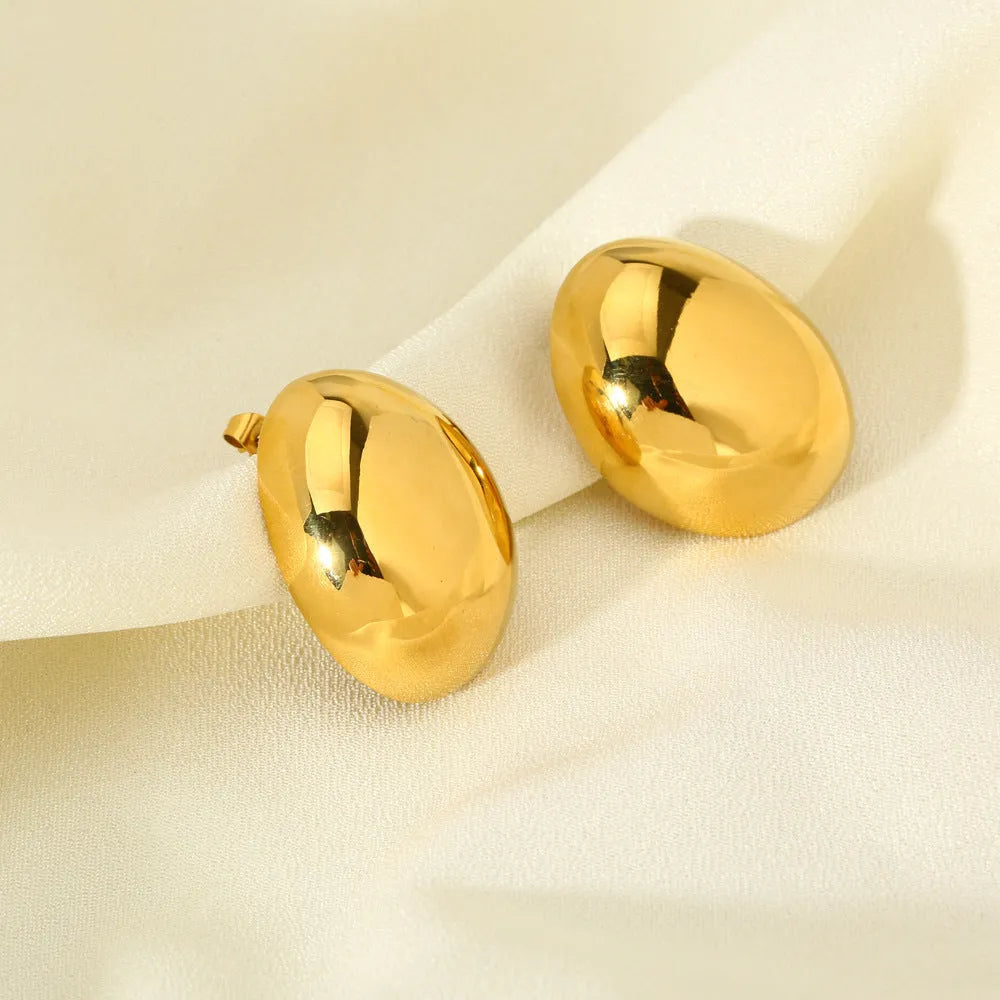A pair of geometric gold-coloured ear studs with a glazed reflective surface and linear design details.
