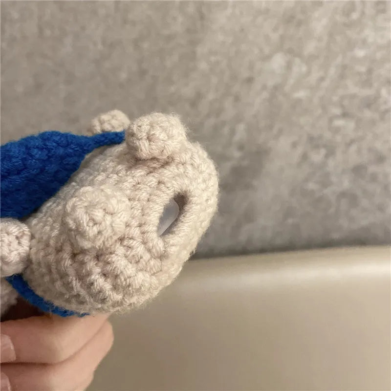 Hand-knitted grey koala bear backpack design earphone cover for Apple AirPods on a table.