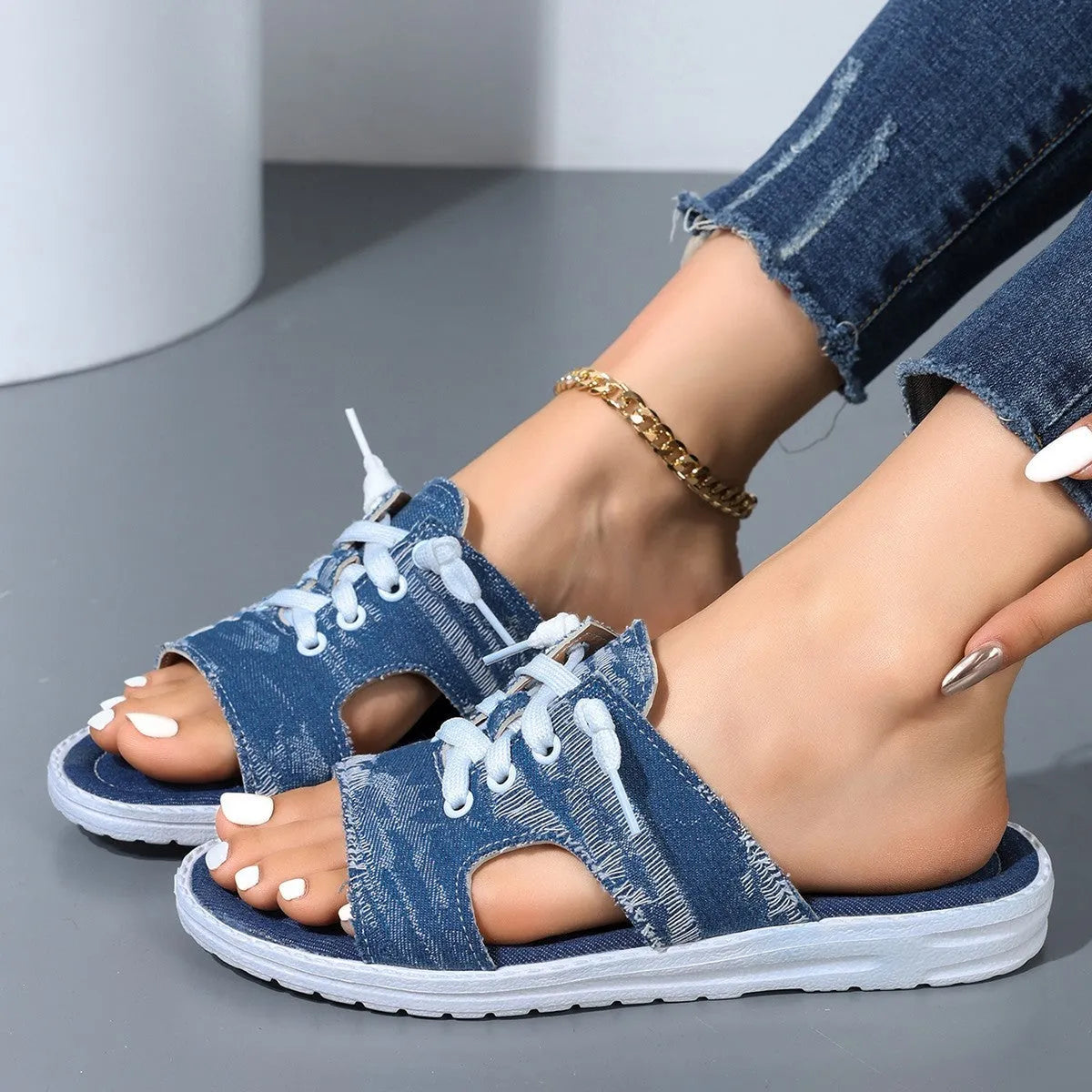 Blue Roman style women's flat canvas slippers with cloth upper and rubber sole.