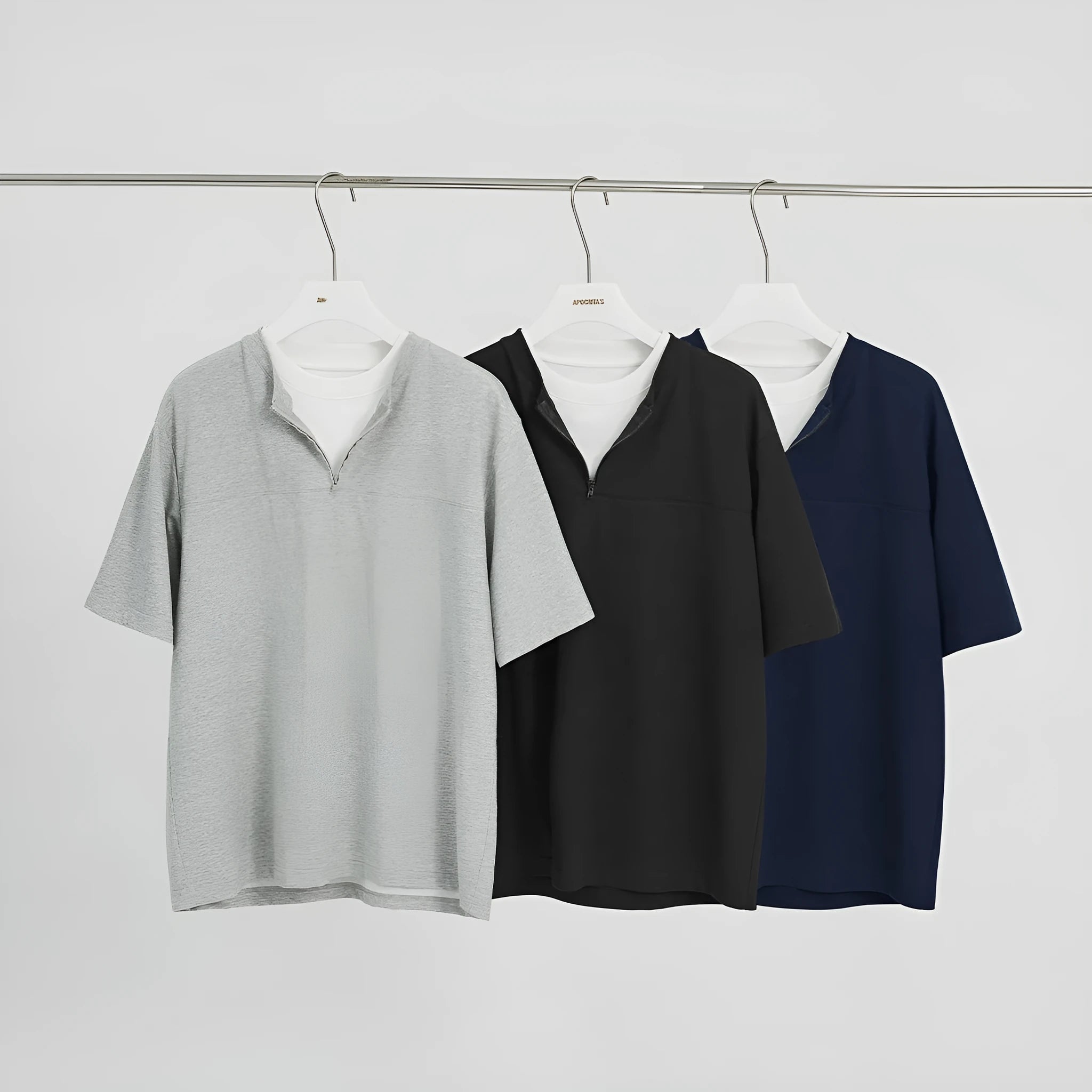 A solid colour loose-fitting casual top with zip detail and patchwork styling on a hanger.