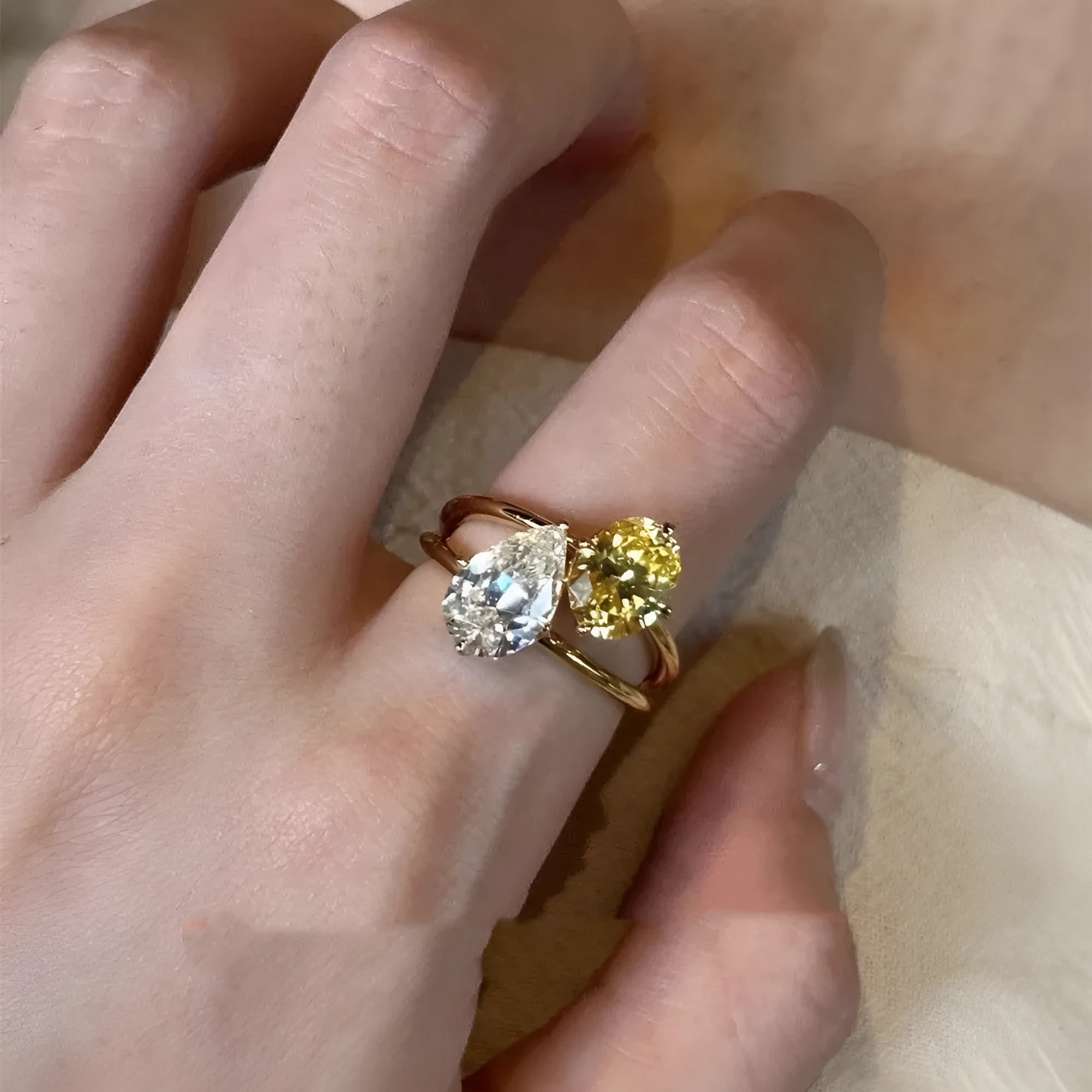 Copper geometric open ring with double zircon stones in a water drop design on a person's finger.