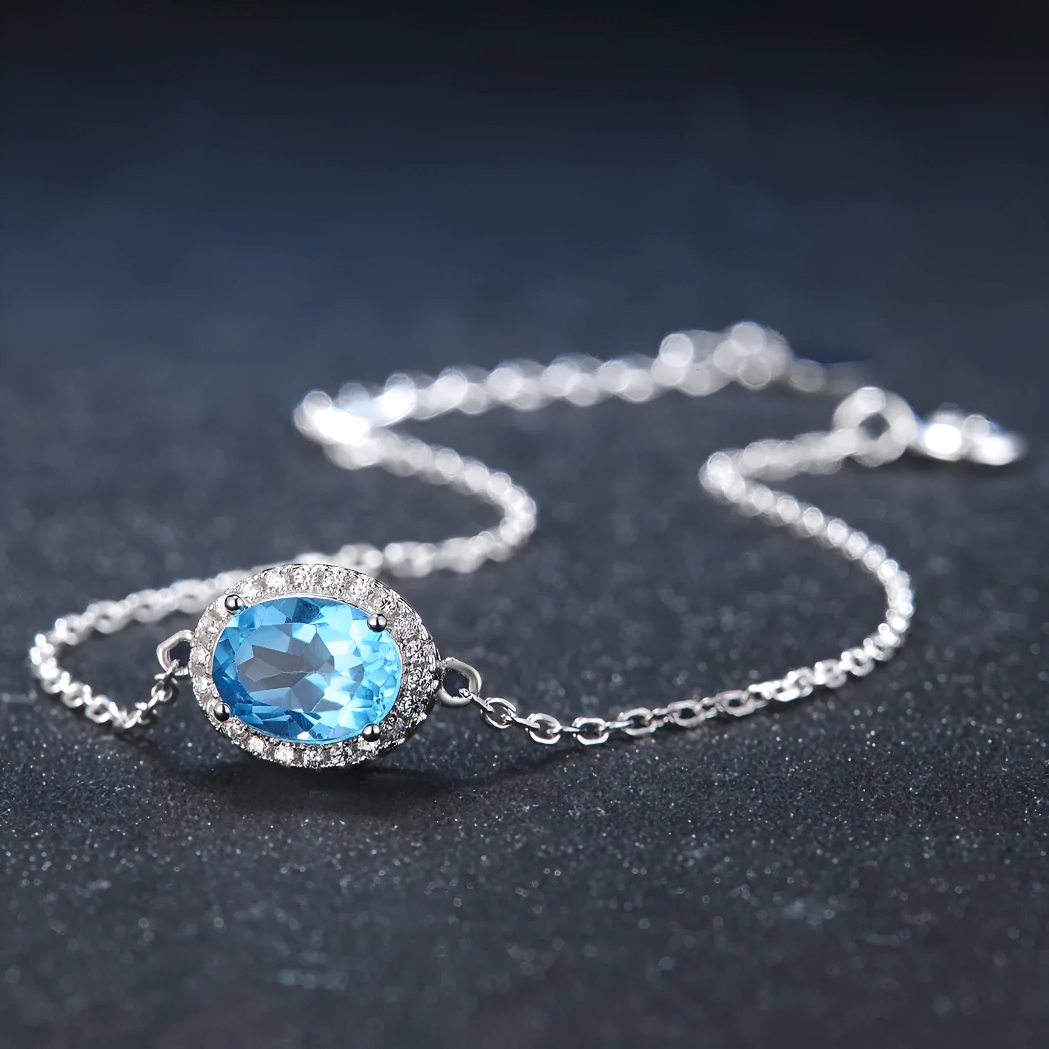 Geometric women's jewellery set in sterling silver with blue topaz gems, showing necklace, earrings, ring, and pendant.