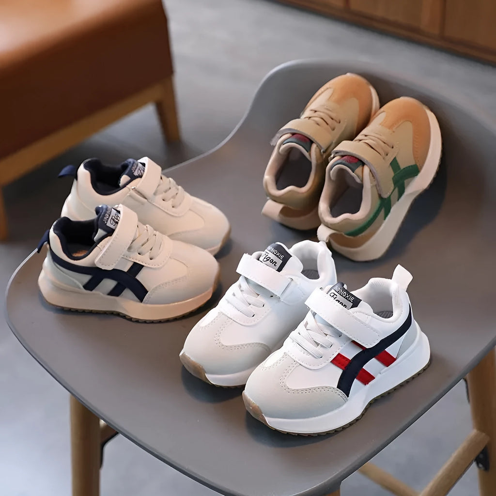 White children's sneakers with Velcro strap and textured rubber sole on a neutral background