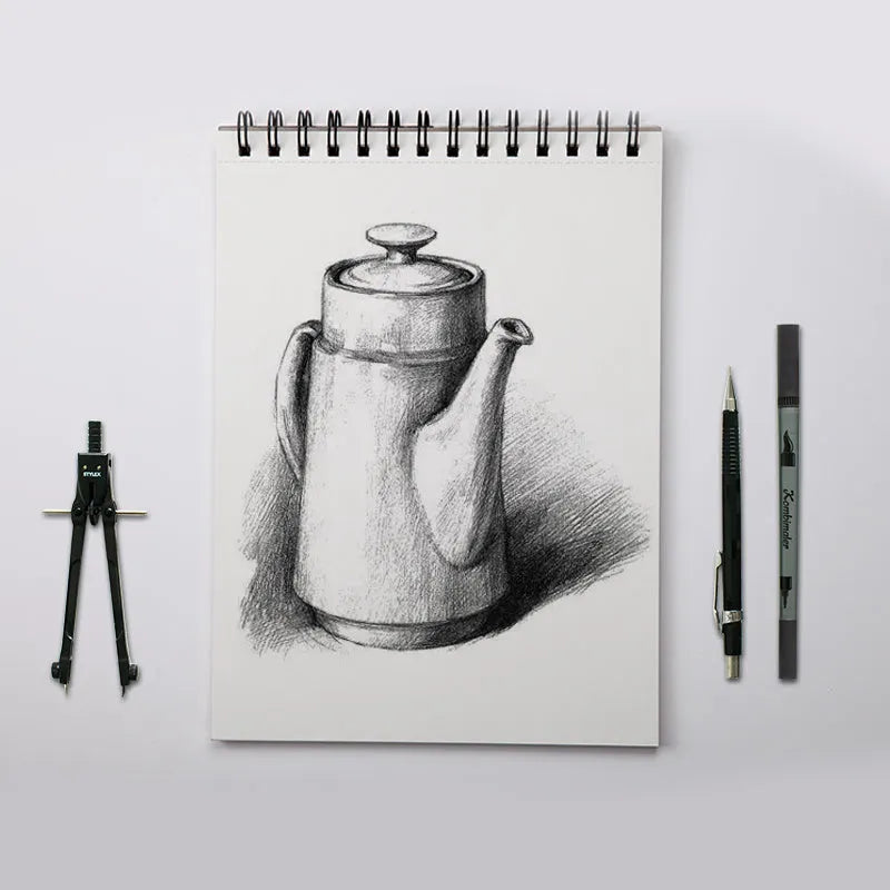 A sketchbook open on a table, showing coil binding and heavy-weight paper suitable for drawing.