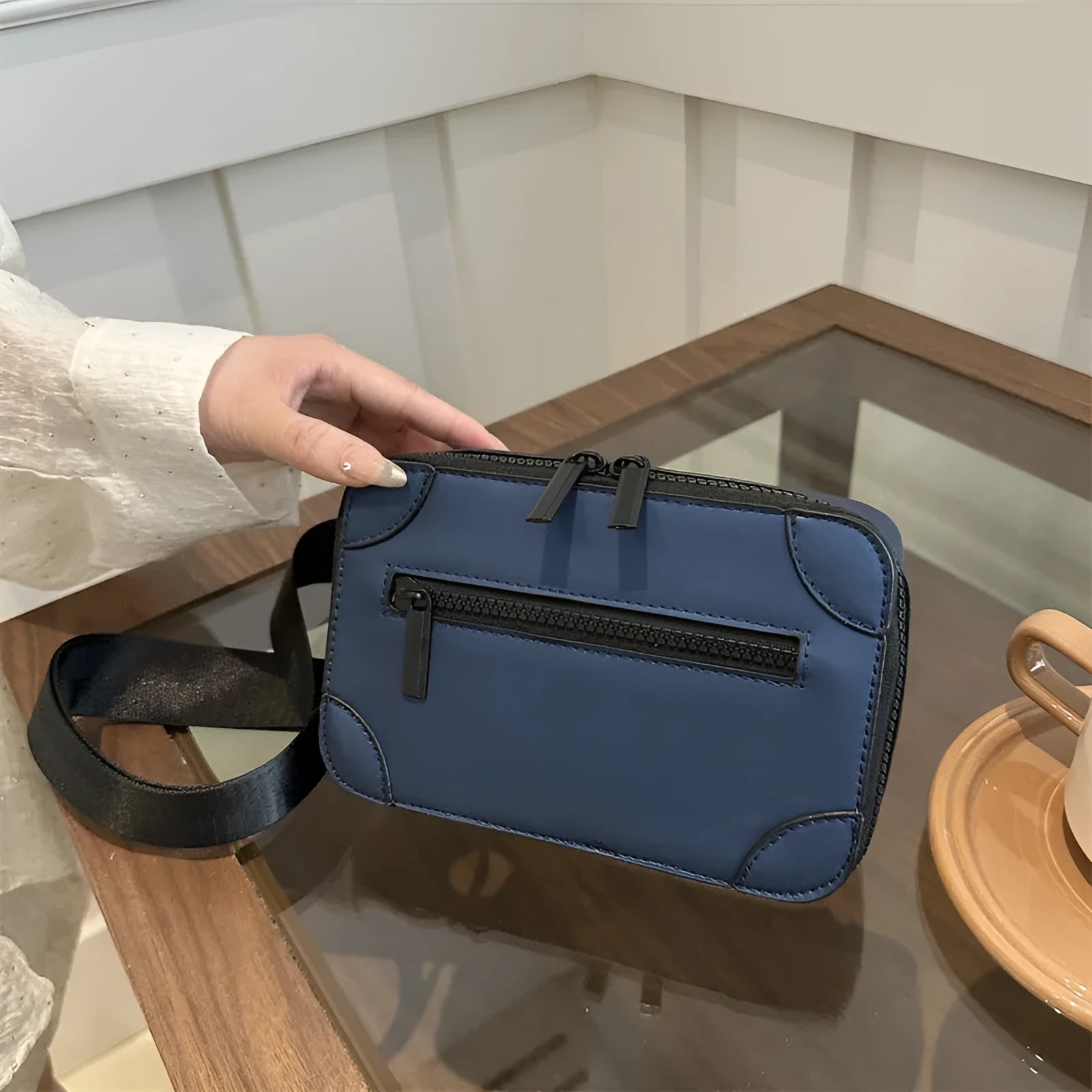 A small, square, structured crossbody bag in a choice of colours, showing its horizontal shape and sewing line detailing.