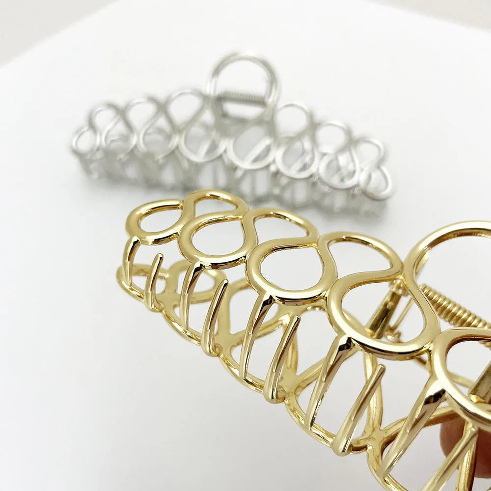 Minimalist large hair clip with gold electroplated finish and tassel detail on irregular geometric alloy design