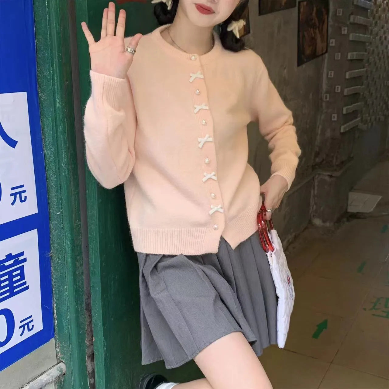 Women's cardigan sweater with a bow and pearl buttons in a solid colour.