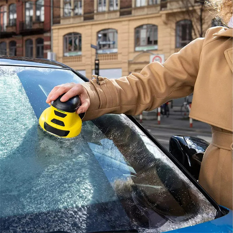 Yellow cordless electric car ice scraper with USB charging cable on a frosty car windscreen.