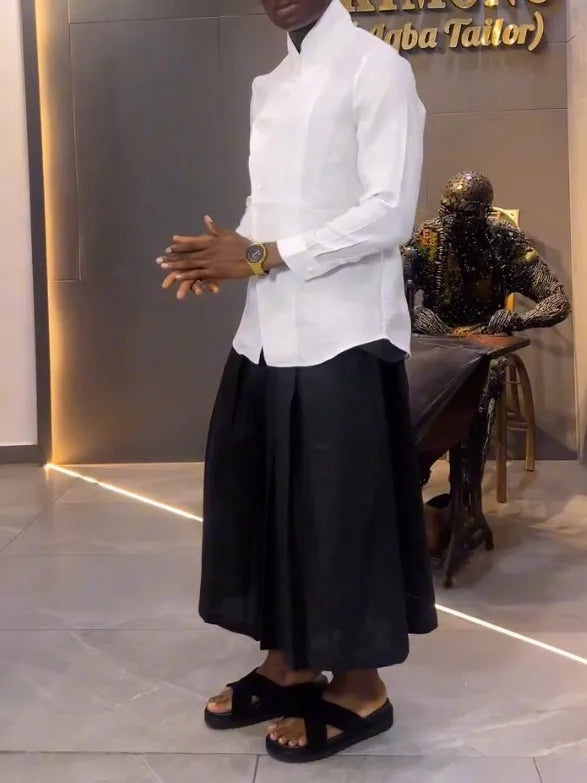 White asymmetrical shirt and black pleated trousers co-ordinate set laid flat