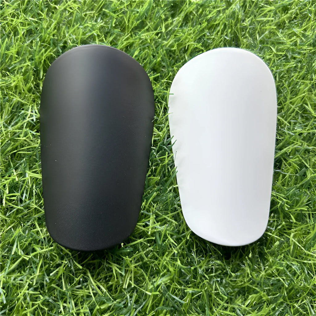 Extra small mini plastic football shin guards in black and white, shown at 8cm by 5cm size.