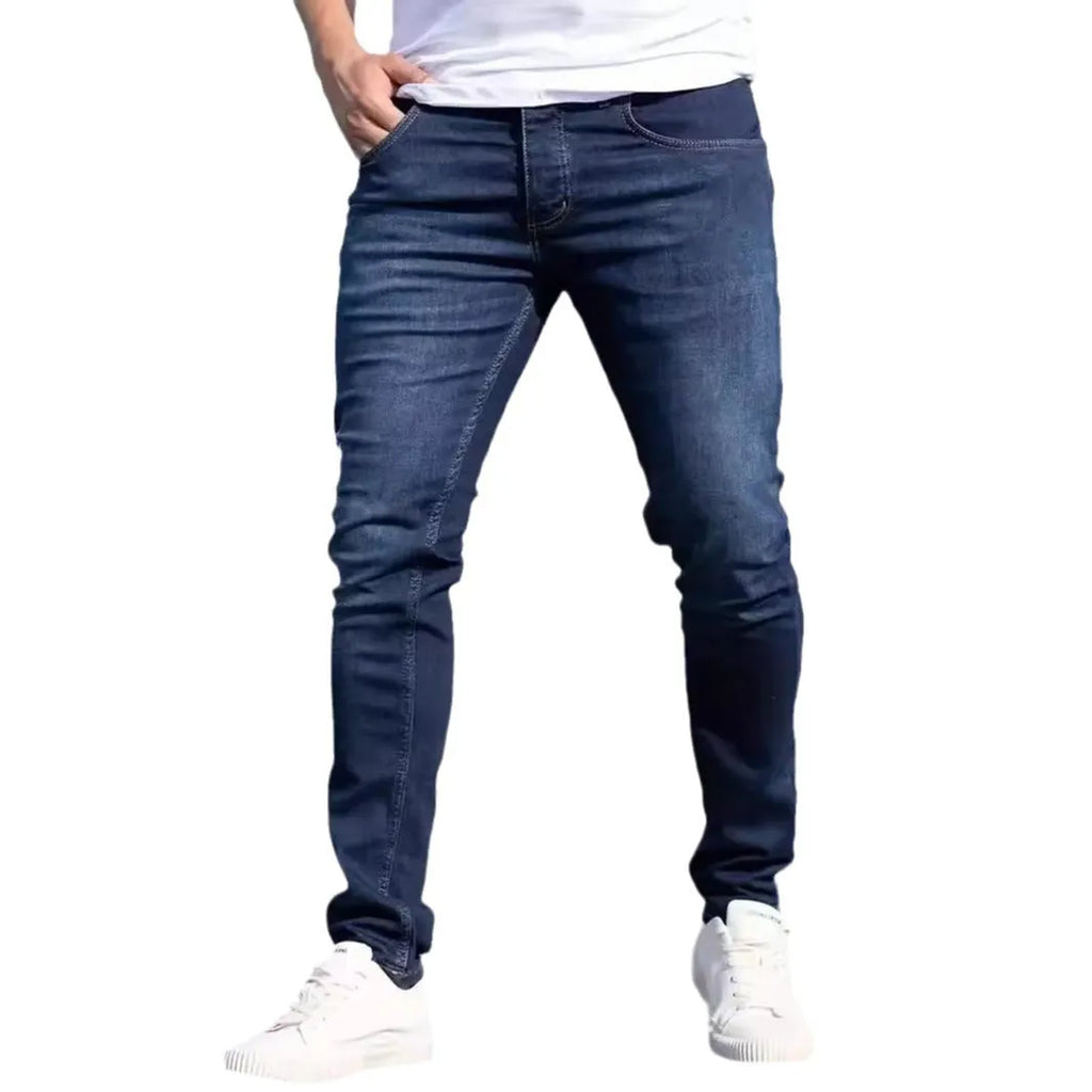 Men's dark blue slim fit skinny jeans on a hanger, showing mid waist and zipper fly detail.
