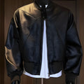 Man wearing a long black PU leather jacket with a tight fit and light business style.