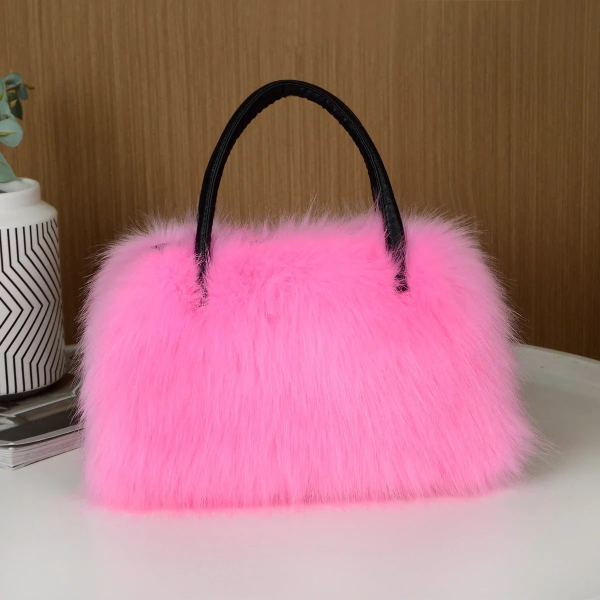 Hand-carrying square plush bag in pink with soft faux fur exterior and horizontal shape