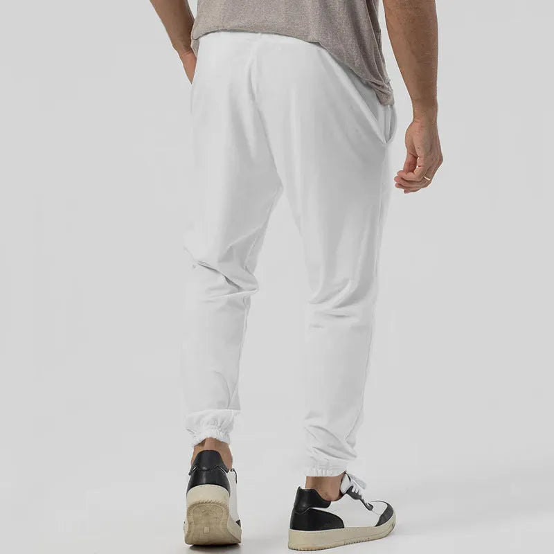 Man wearing grey tapered straight-leg casual sweatpants with a mid-rise elastic waistband.