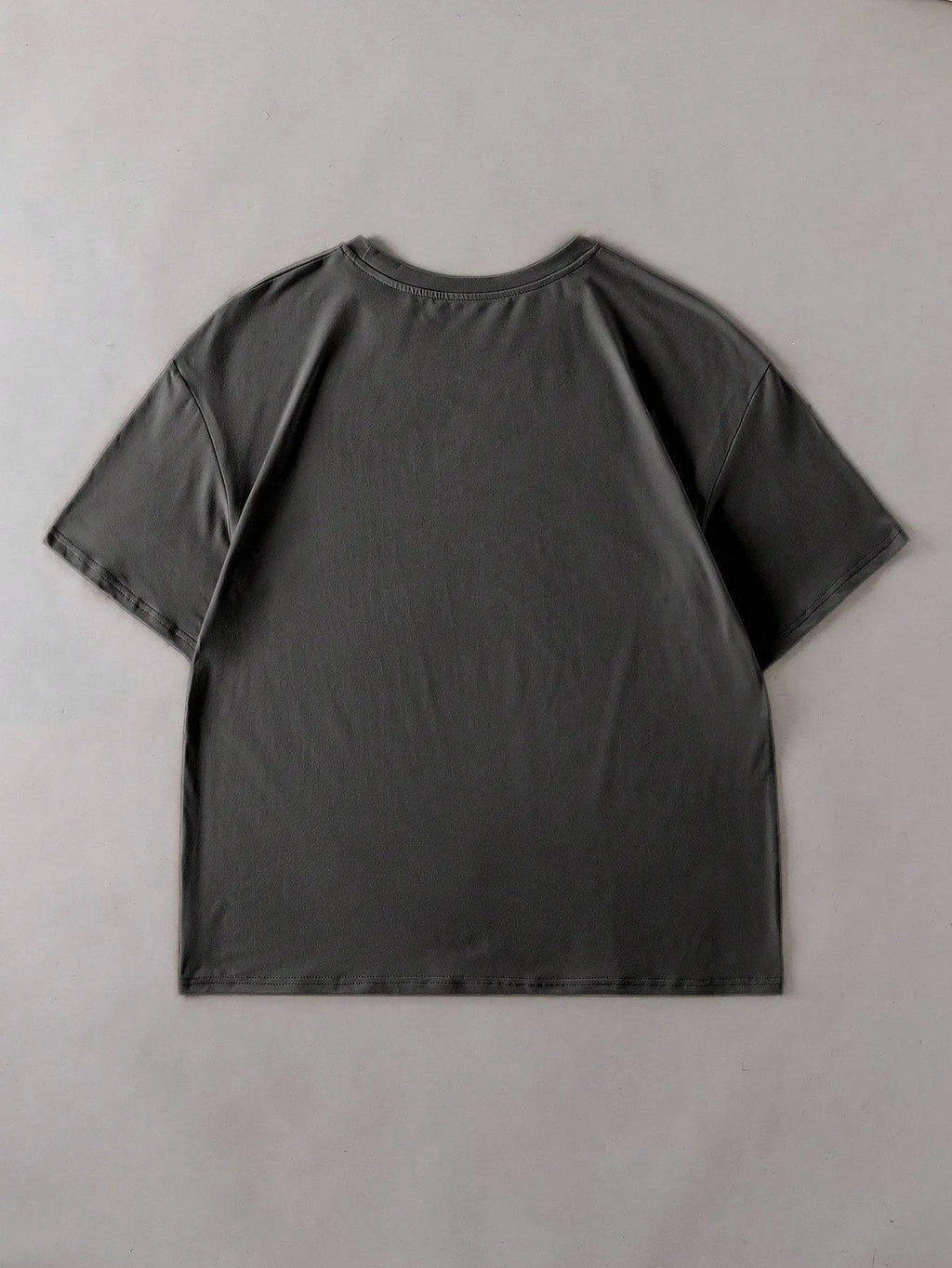 A loose-fitting black cotton t-shirt with short sleeves and a round neck on a hanger.