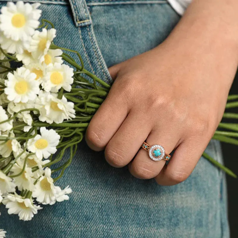 Women's turquoise ethnic geometric ring with micro inlaid zircon in rose gold coloured copper on a white background.