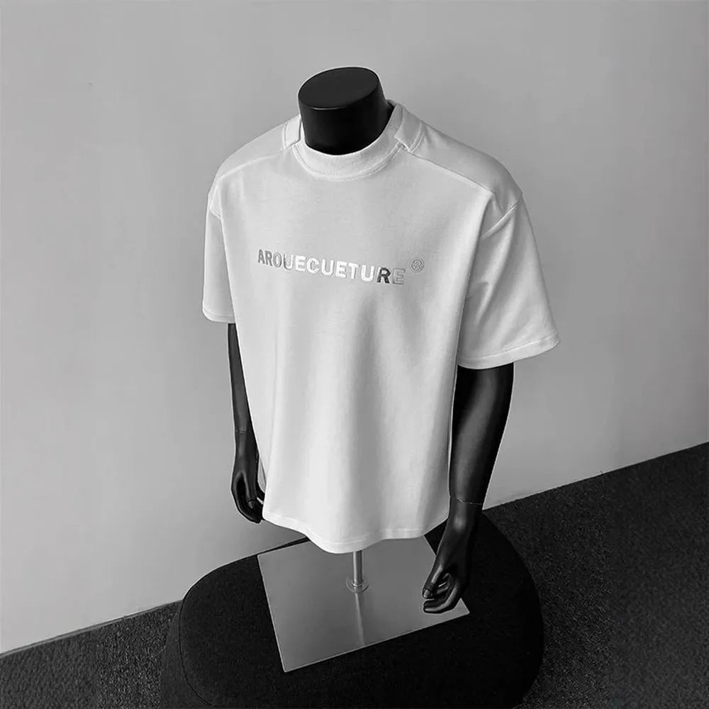 Man wearing a loose grey short sleeve cotton shirt with a letter print design.