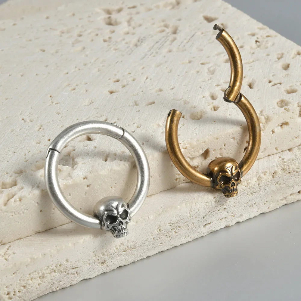 Close-up of vintage-style copper stud earrings featuring a detailed stamped ghost head motif with an antique silver finish.