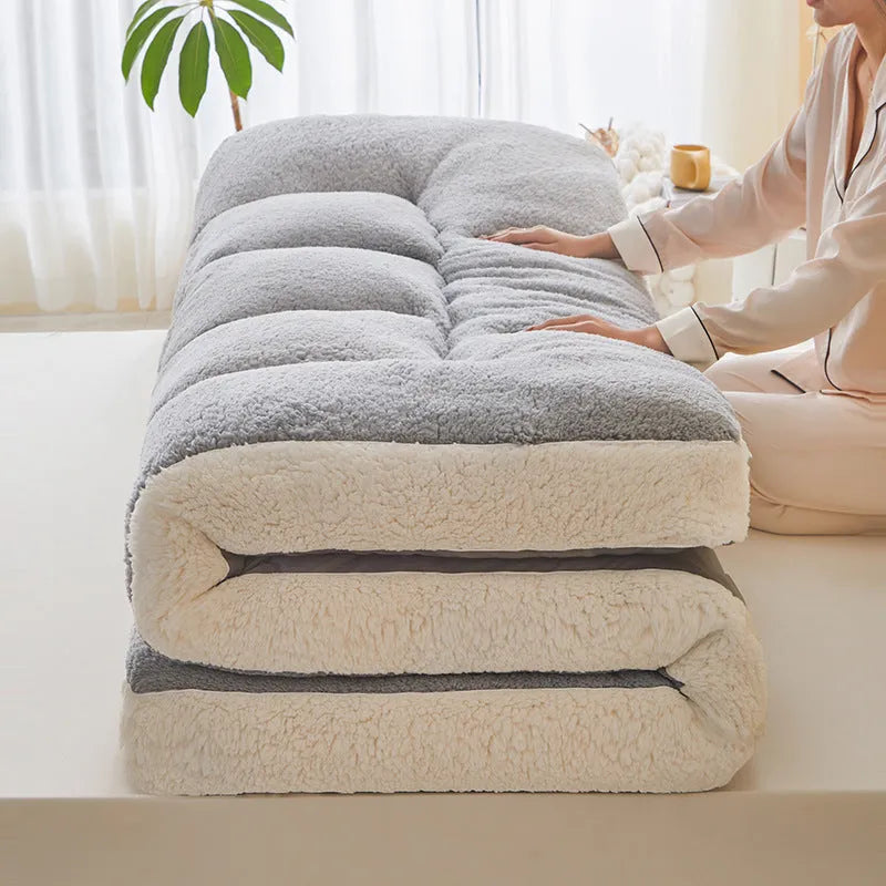 Lambswool mattress cushion with velvet cover in grey and white edge, on a bed