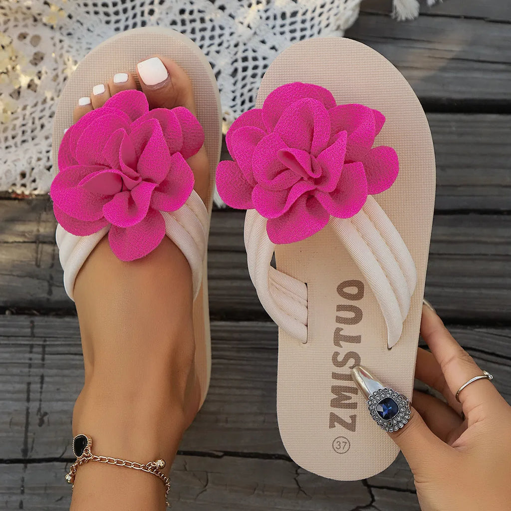 A pair of solid colour flip flop slippers with a small flower detail on the PU upper.