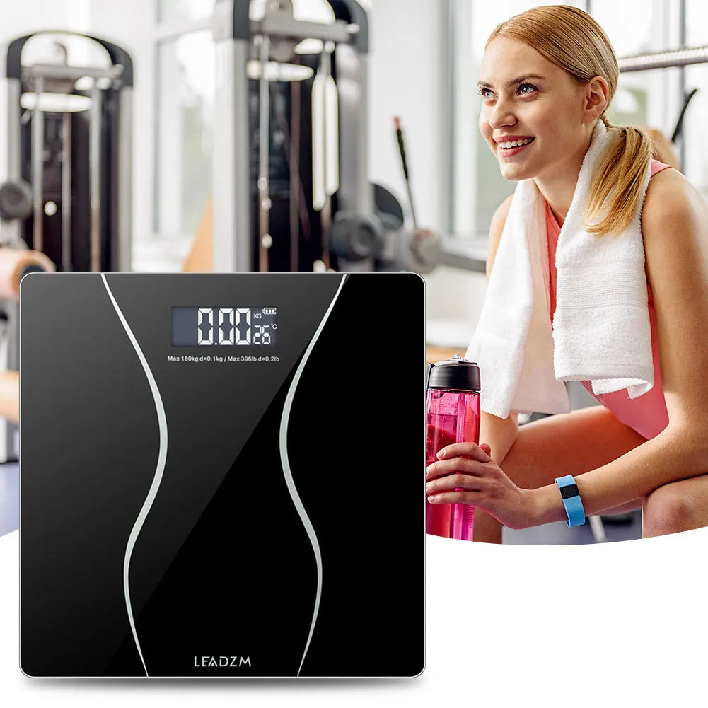 A black electronic body scale with a digital display on a hard floor.