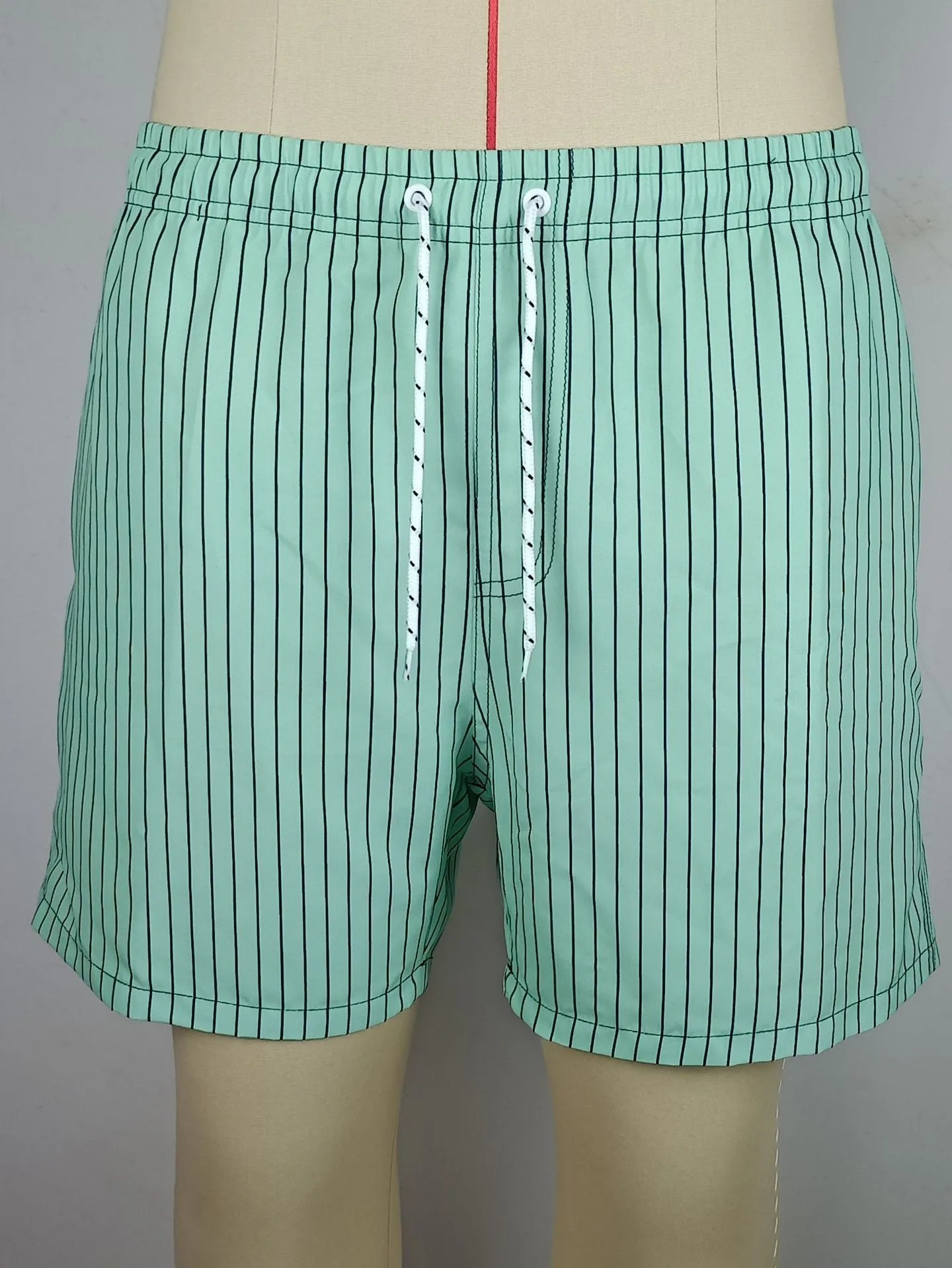Man wearing grey striped polyester beach shorts with a straight leg opening