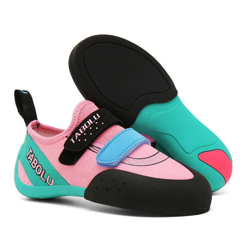 Black and red beginner rock climbing shoes with velcro strap and rubber sole on a climbing hold.