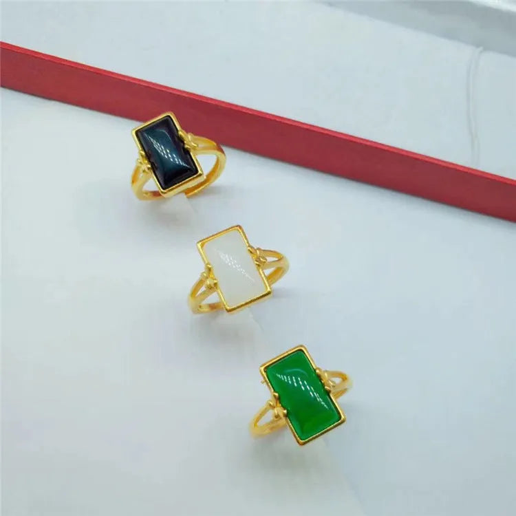 Adjustable brass gold-plated ring with a green artificial gemstone inlay on a finger.