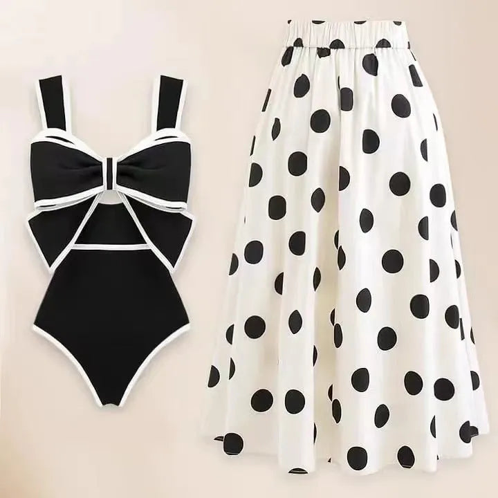 Black one-piece swimsuit for women with a white bow on a short round skirt, showcasing the beach dress style.