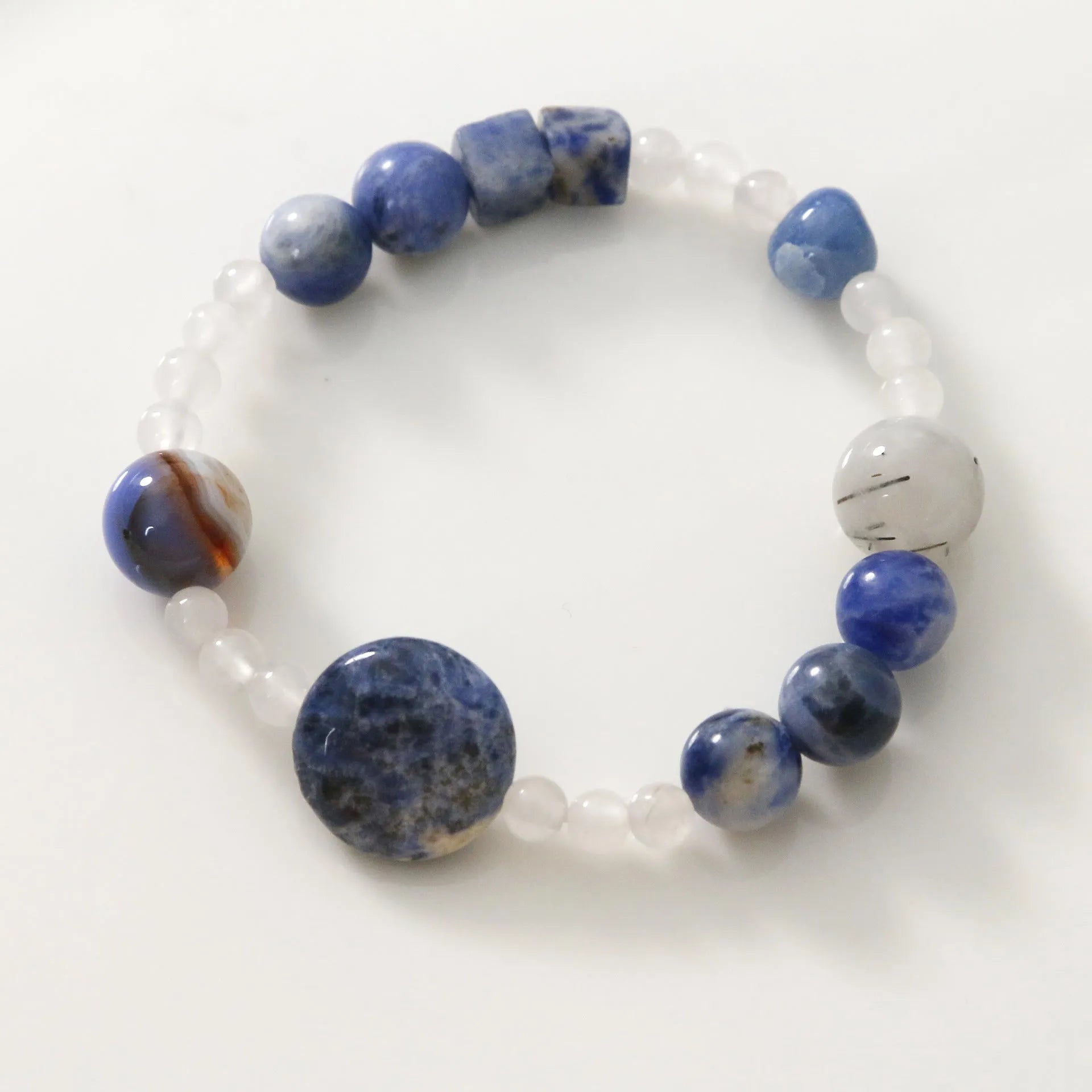 Hand-woven unisex bracelet with blue point stone and black hair crystal agate in a geometric design.