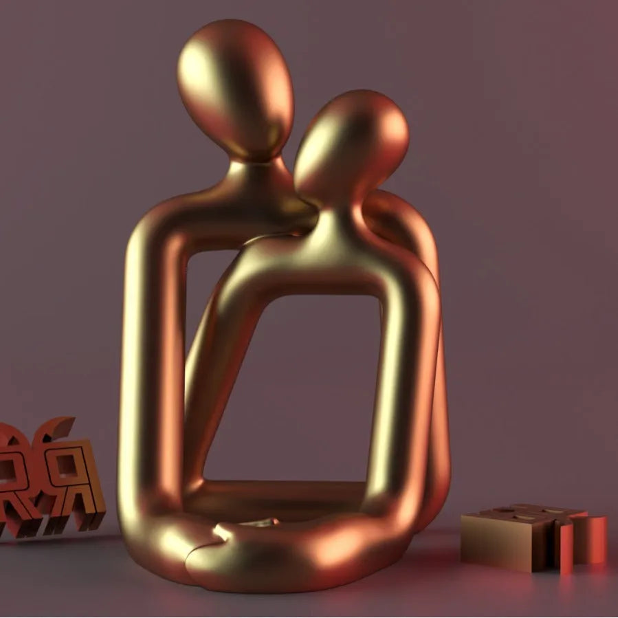 Modern loving couple resin statue in milky white or gold colour on a desk.