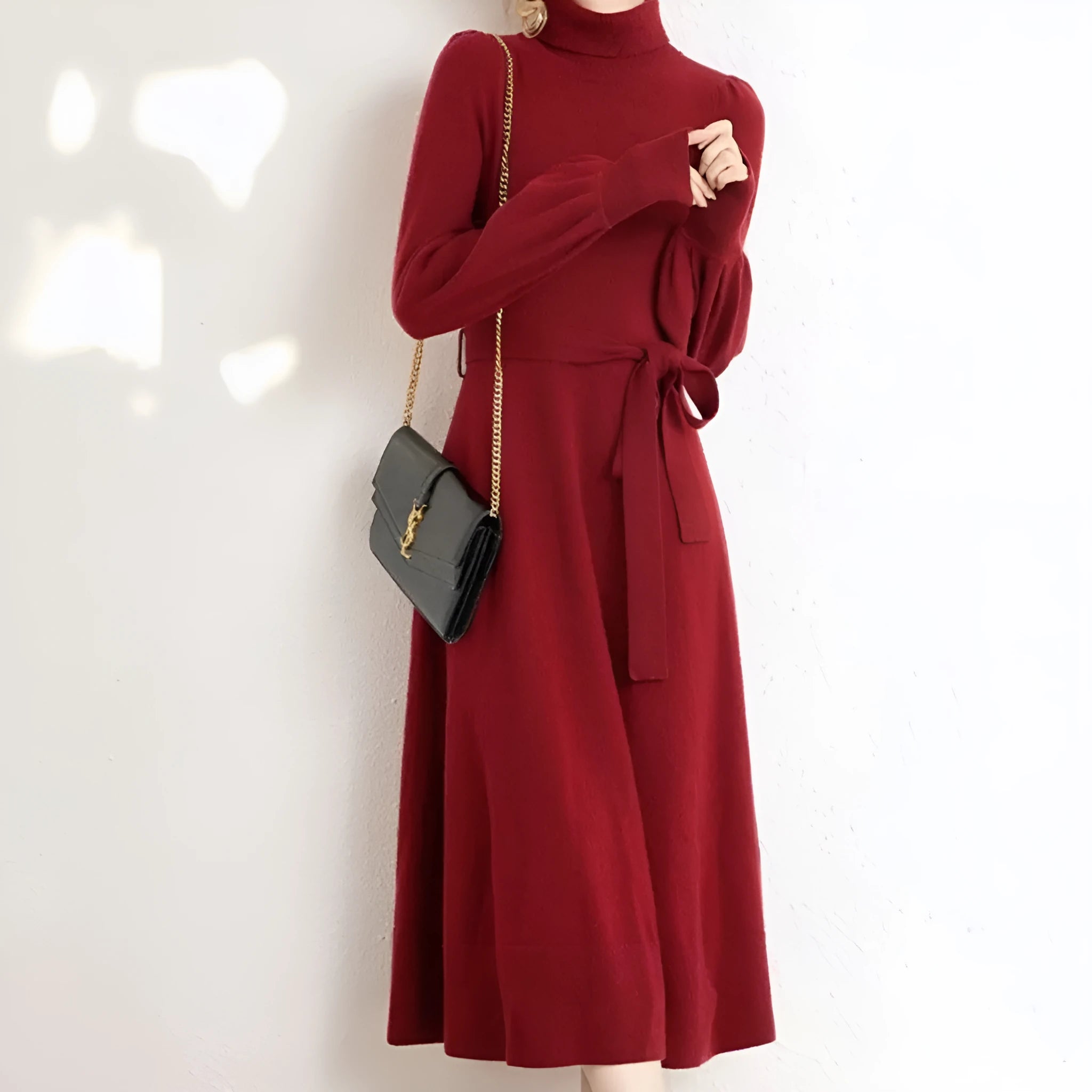 A woman wearing a rose red loose knitted turtleneck dress with a big hem midi skirt.