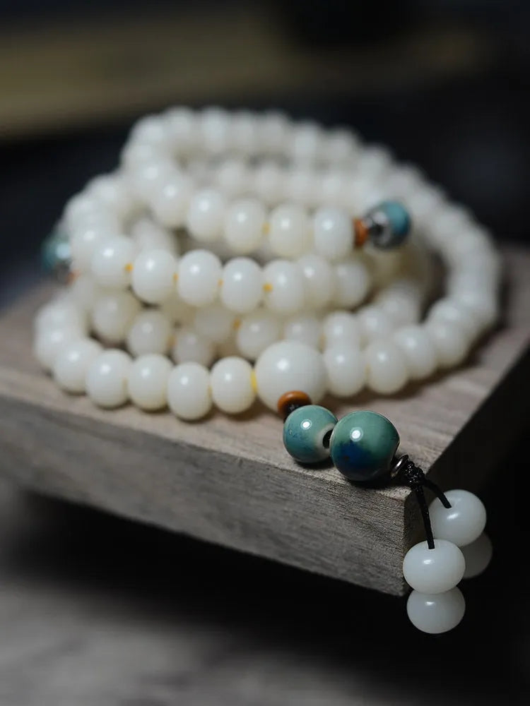 White jade bodhi root oblate bead bracelet with 108 flat round beads in 7x9mm and 8x10mm sizes.