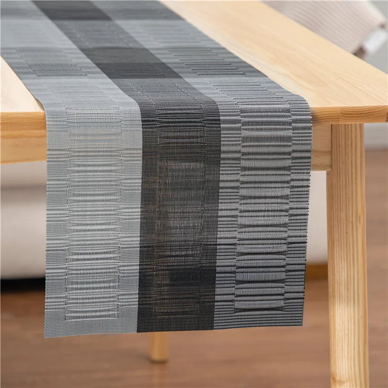 Modern non-slip PVC dish mat with gradient bamboo pattern in black, placed on a wooden dining table.