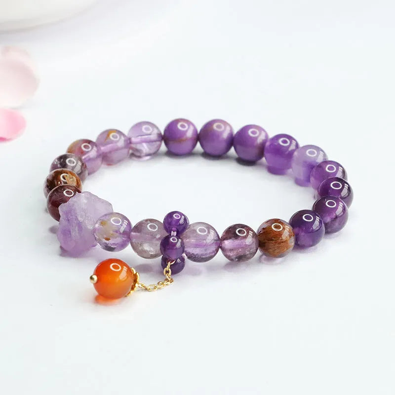 Nine purple fire amethyst and red agate Mori-style crystal bracelet on a wrist.