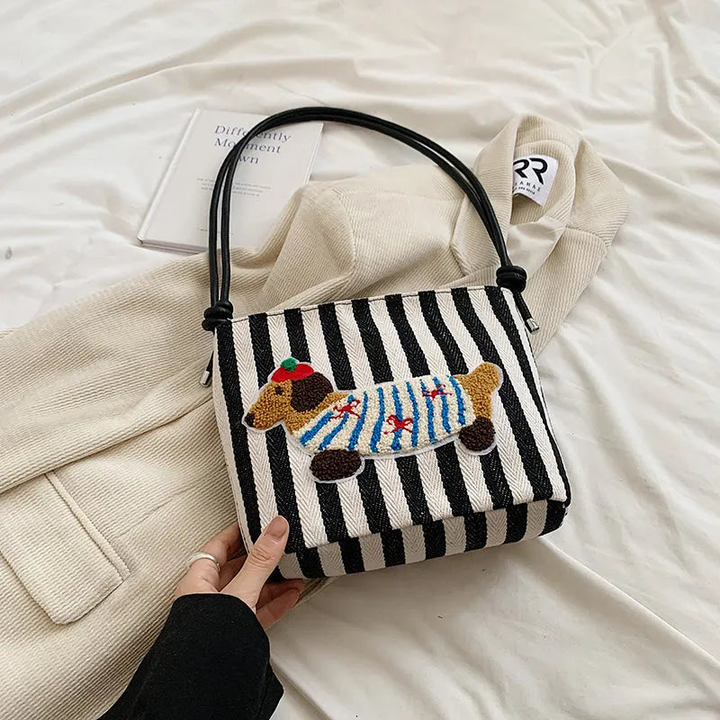 Cartoon sausage dog bucket bag in polyester with canvas lining, soft crossbody shape and single strap.