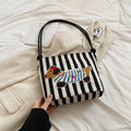 Cartoon sausage dog bucket bag in polyester with canvas lining, soft crossbody shape and single strap.