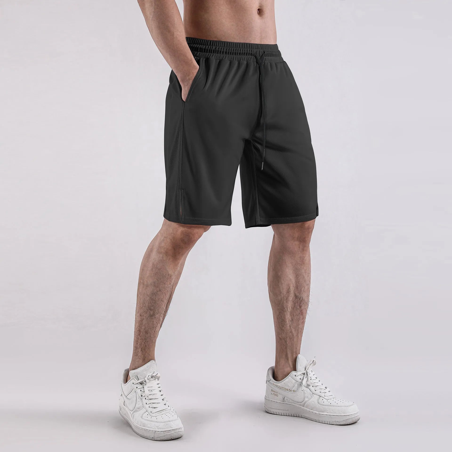 Man wearing black loose-fit quick-dry mesh Capri shorts for summer fitness.