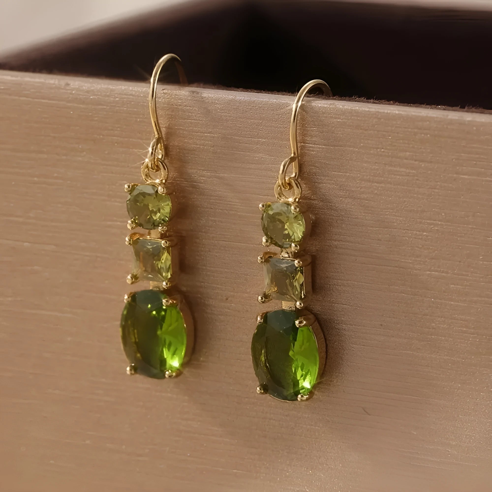 Green geometric copper earrings with a quadrilateral shape on a plain background.