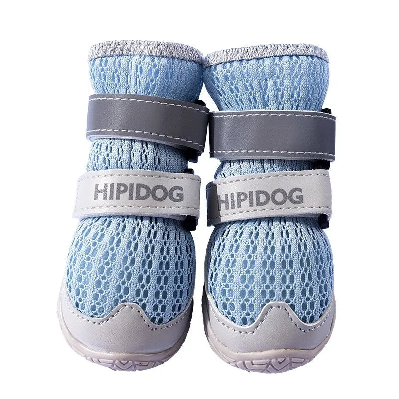 Pair of light blue cartoon-style dog shoes with adjustable strap, shown on a dog's paw.