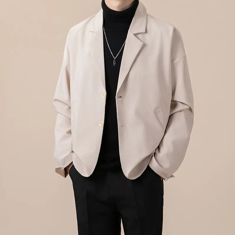 Man wearing a loose fit apricot coloured suit jacket with long sleeves.
