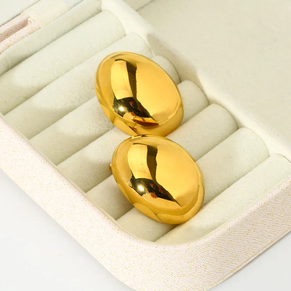 A pair of geometric gold-coloured ear studs with a glazed reflective surface and linear design details.