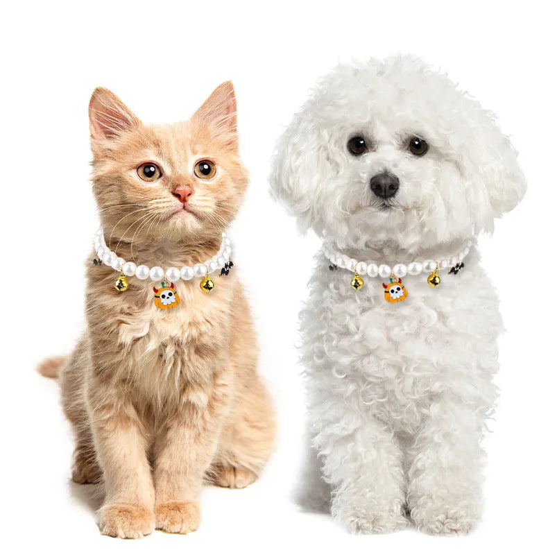 Set of three pet necklaces: a pearl strand, a Halloween cat collar, and a dog bell ornament on a table.