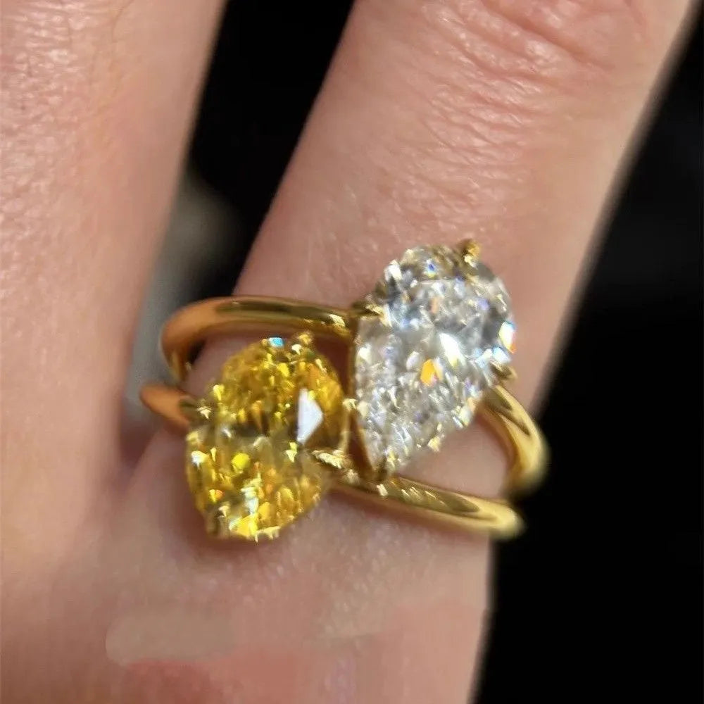 Copper geometric open ring with double zircon stones in a water drop design on a person's finger.