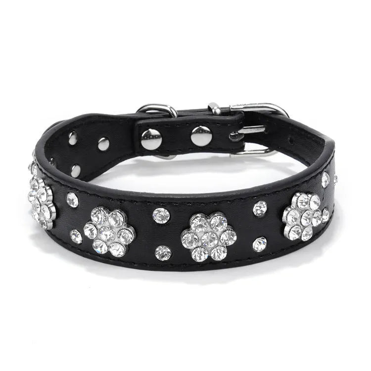 A black PU leather dog collar decorated with sparkling rhinestone flowers and metal studs, showing the adjustable eyelets and metal D-ring.
