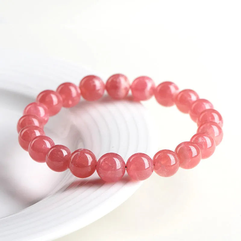 Women's geometric rhodochrosite crystal bracelet with a longevity lock clasp on a wrist.