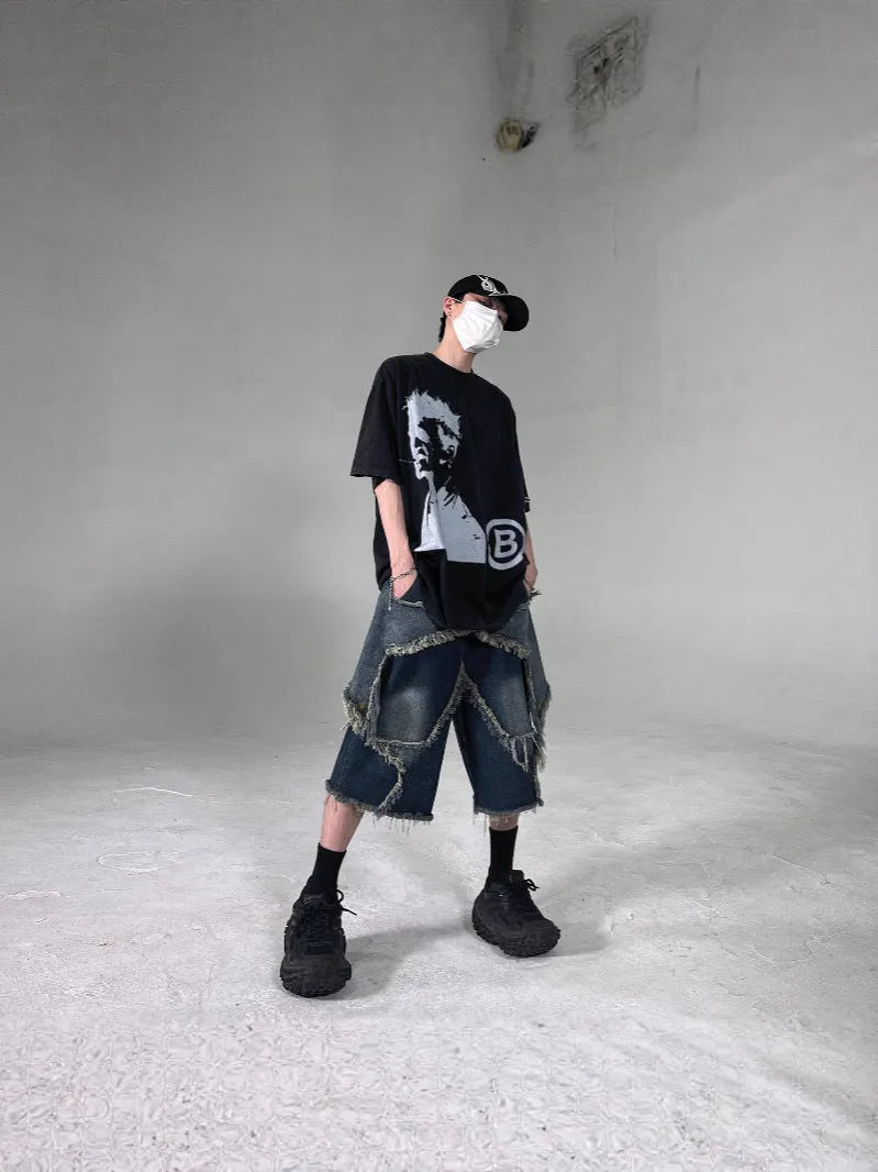 Man wearing blue loose-fit denim shorts with frayed five-pointed star embroidery on the leg.